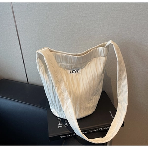 Detailed close-up of ivory bucket bag with pleated texture and LOVE patch accent