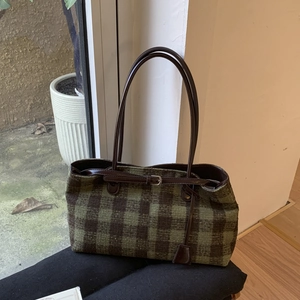 Detail of vintage green plaid tote bag with brown leather straps and metal buckle