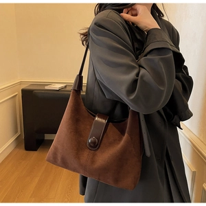 Detail of dark brown suede hobo bag featuring vintage stitching and polished leather strap