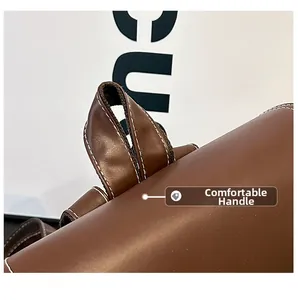 Close-up of brown leather bag handle with precise white contrast stitching detail