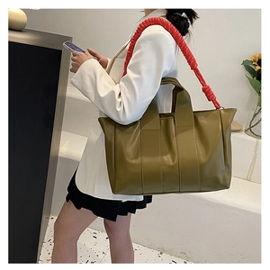 Borsa tote verde oliva con tracolla a treccia rossa indossata da una modella