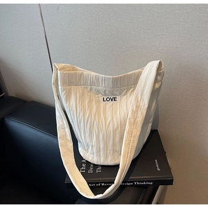 Detail of cream quilted bucket bag with LOVE label placed on a black book