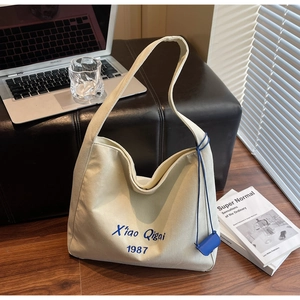 Dettaglio della borsa tote in tela beige con ricamo blu e mini custodia abbinata