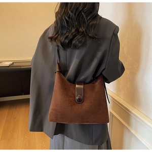 Brown suede minimalist hobo bag with smooth leather strap shown on a model's shoulder