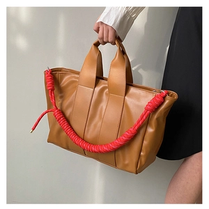 Dettaglio della borsa tote marrone con corda rossa intrecciata e doppi manici