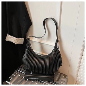 Detail of black pleated crossbody bag with fine vertical texture and golden zipper