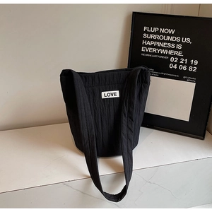 Detail of the black pleated fabric texture and LOVE fabric label on the casual tote bag