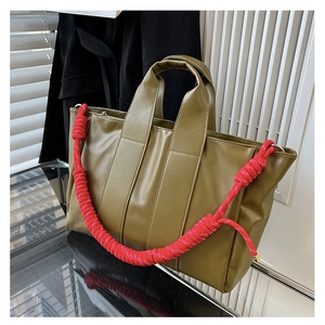 Dettaglio borsa tote verde oliva con manici in corda intrecciata rosa e cuciture a contrasto