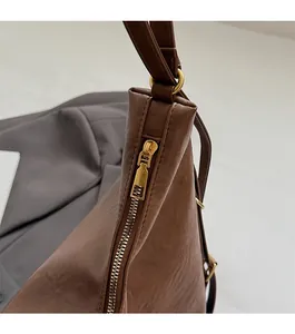 Close-up of a smooth gold metal zipper and strap ring on a brown vintage tote bag