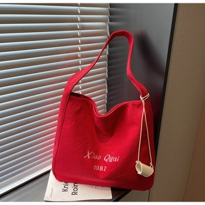 Dettaglio della borsa tote in tela rossa con ricamo bianco e ciondolo a corda decorativa