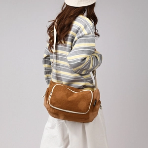 Detail of caramel nylon crossbody bag with white piping and adjustable strap