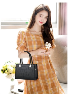 Elegant black crocodile embossed handbag with woven handle and luxury gold hardware