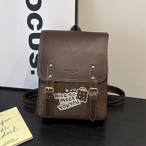 Close-up of the vintage brown leather backpack with golden buckles and embroidery detail