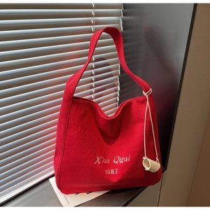 Dettaglio della borsa tote in tela rossa con ricamo bianco e base cilindrica
