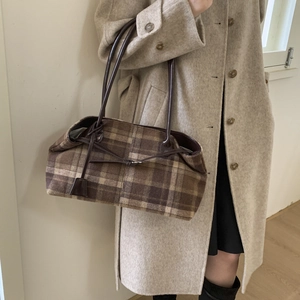 Close-up of brown plaid tote bag with decorative bow and premium leather handles