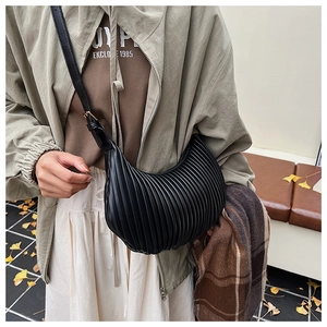Detail view of the black pleated crescent bag featuring premium texture and adjustable strap