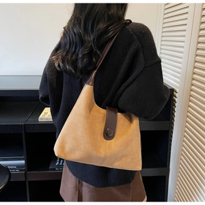 Close-up of a vintage brown suede hobo bag with deep brown leather trim on a model