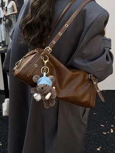 Brown leather Boston bag with teddy bear charm shown on model in grey blazer