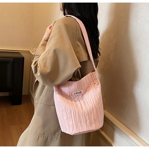 Detail of pink pleated tote bag featuring a decorative LOVE label and textured fabric
