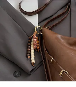 Close-up of ethnic beaded charm and vintage dark brown leather texture on tote bag