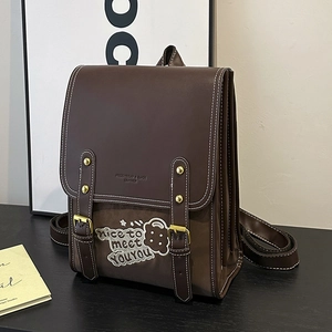 Detail of a brown leather backpack with retro embroidery and metal buckle closure