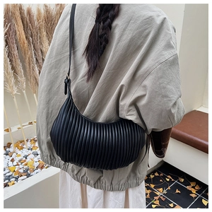 Macro detail of black pleated leather crescent bag showing vertical texture and strap