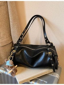 Retro black cylinder tote bag with metal eyelet straps and cute bear charm in soft lighting