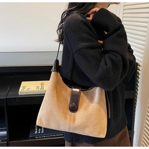 Detailed view of the khaki suede texture and brown leather buckle on a retro shoulder bag