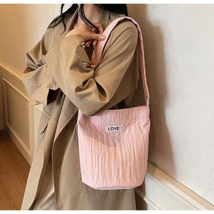 Detailed shot of pink pleated bucket bag with LOVE patch and textured fabric surface