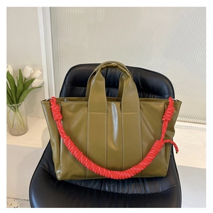 Dettaglio di una borsa tote verde oliva con un cinturino in corda intrecciata rossa
