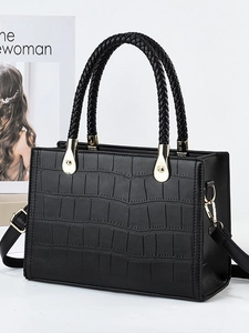 Elegant black crocodile embossed handbag with woven handles and gold hardware in studio setting