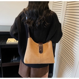 Macro shot of brown faux suede shoulder bag featuring dark leather strap and button closure