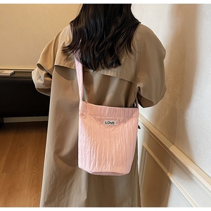 Detailed back view of pink pleated bucket bag with LOVE label on model in casual setting