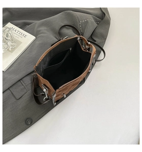 Detail view of the dark brown suede bag interior showing silver zipper and black fabric lining