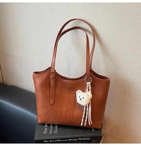 Brown faux leather tote bag with gold logo and cute white teddy bear charm accessory