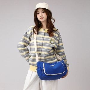 Macro shot of durable blue nylon crossbody bag with wide cream canvas strap and zipper detail