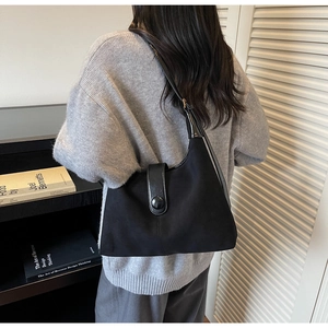 Detail of black crescent shoulder bag featuring suede and patent leather contrast textures