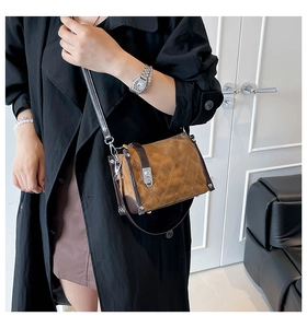 Close-up of quilted brown crossbody bag featuring elegant metal lock and leather strap