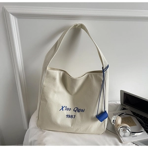 Dettaglio della borsa tote in tela con ricamo blu e mini tasca laterale come accessorio