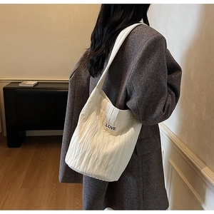 Detail of the white pleated fabric texture and LOVE patch on this stylish tote bag