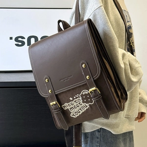 Detail of vintage brown PU leather backpack with gold buckle and embroidery patch