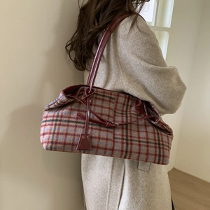 Detail of plaid tote bag with red leather strap and drawstring closure in studio