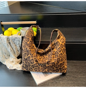 Detailed view of leopard print canvas hobo bag with leather strap on vintage wooden steps