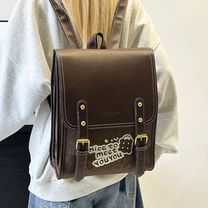 Detail of vintage brown leather backpack with retro bear pattern and white stitching