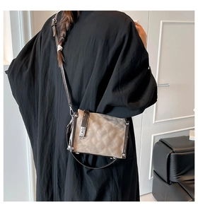 Detailed back view of a beige crossbody bag with dark brown leather trim and silver clasp