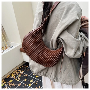 Detail view of dark brown pleated crescent bag with elegant accordion texture and strap