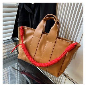 Dettaglio borsa tote marrone con tracolla in corda intrecciata rossa e chiusura lampo