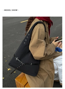 Detail of black hobo shoulder bag featuring silver metal eyelets and adjustable leather straps