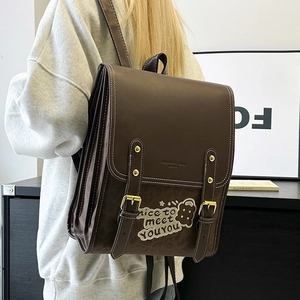 Detail of vintage brown PU leather backpack with bear patch and double buckle closure