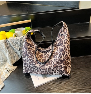Detail view of large leopard print tote bag placed on wooden steps with lifestyle props